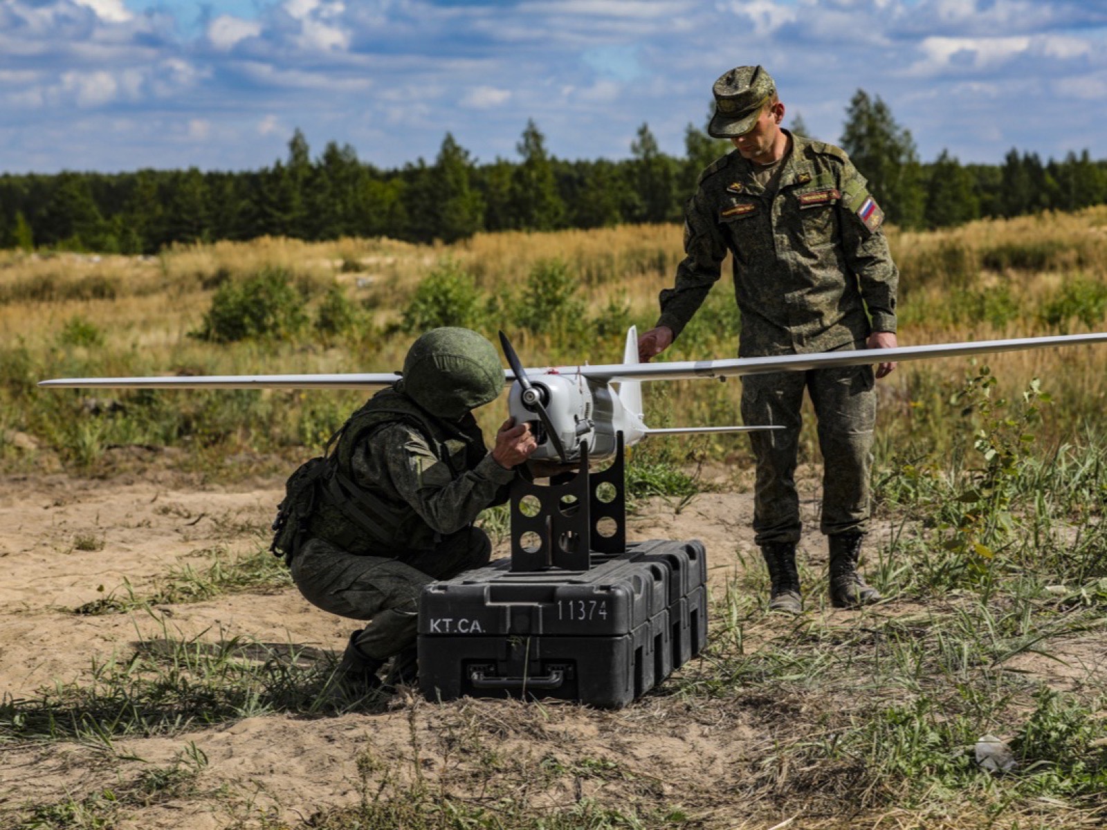 Двое военных у беспилотника «Орлан-10»: аппарат установлен на стойку рядом с транспортным кейсом, один из них его проверяет